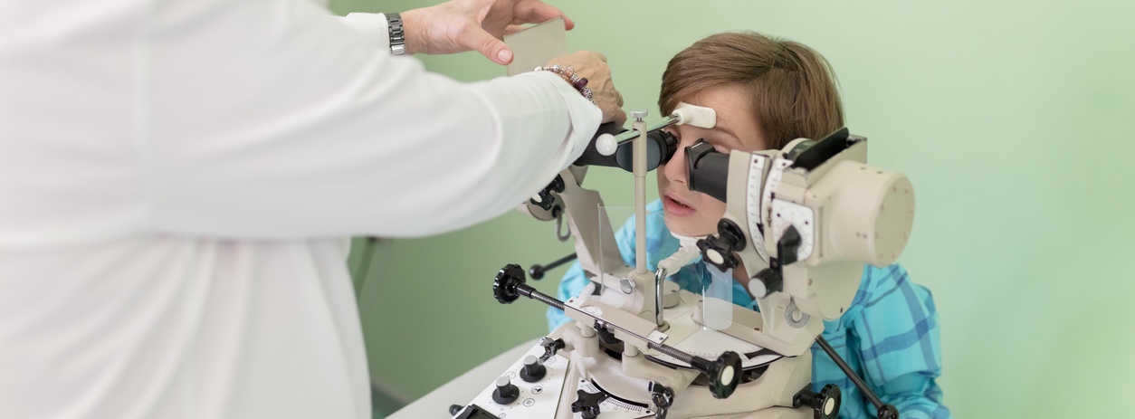 young boy placing head in machine for eye exam