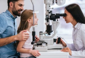 Father and his daughter are checking the eye vision in ophthalmology clinic. 300x206 1