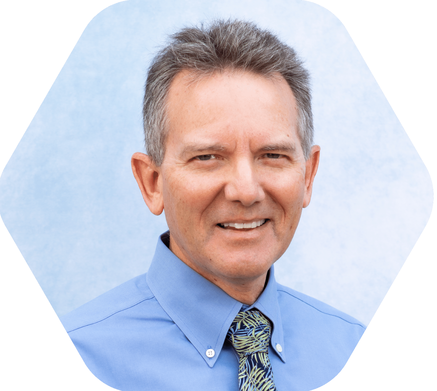 close up headshot of middle aged man smiling with blue dress shirt and tie against light blue and white background