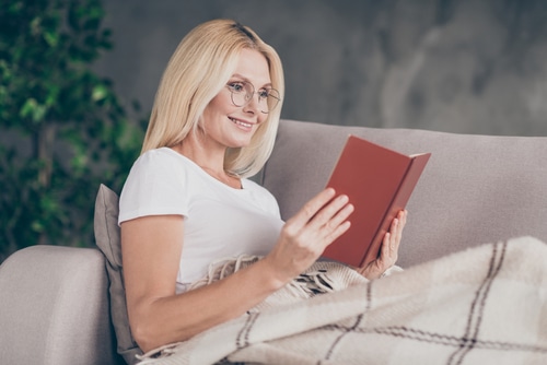 lady sitting on divan reading book in modern industrial loft interior style apartment house