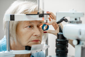 Woman at eye exam with doctor shining light over eye to diagnose for keratoconus