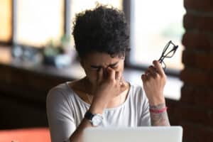 Woman rubbing her eyes after experiencing discomfort due to digital eye strain and screen time