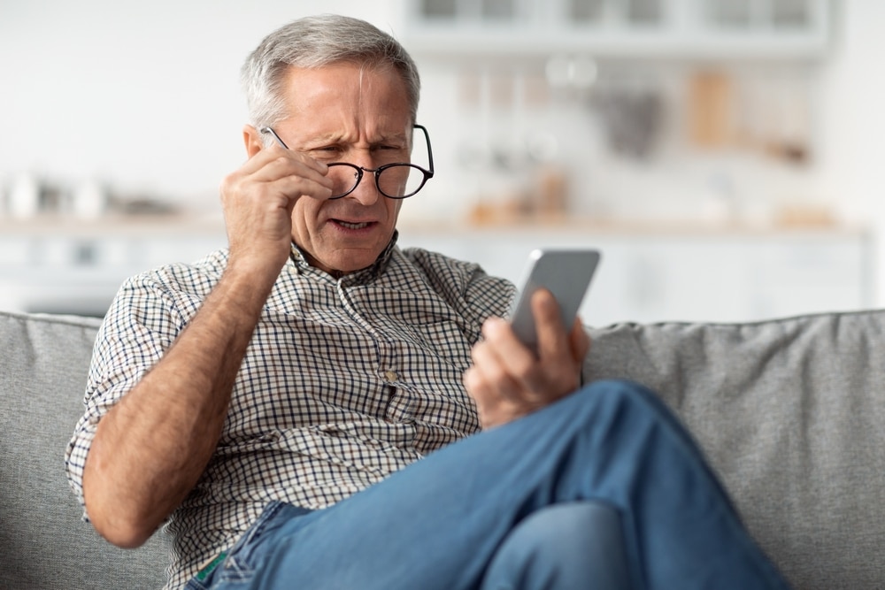 Woman pulling at her eyelid skin Older man struggling to read on phone with glasses