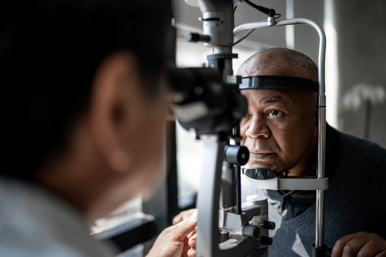 Woman pulling at her eyelid skin Man undergoing a detailed eye examination before cataract surgery.