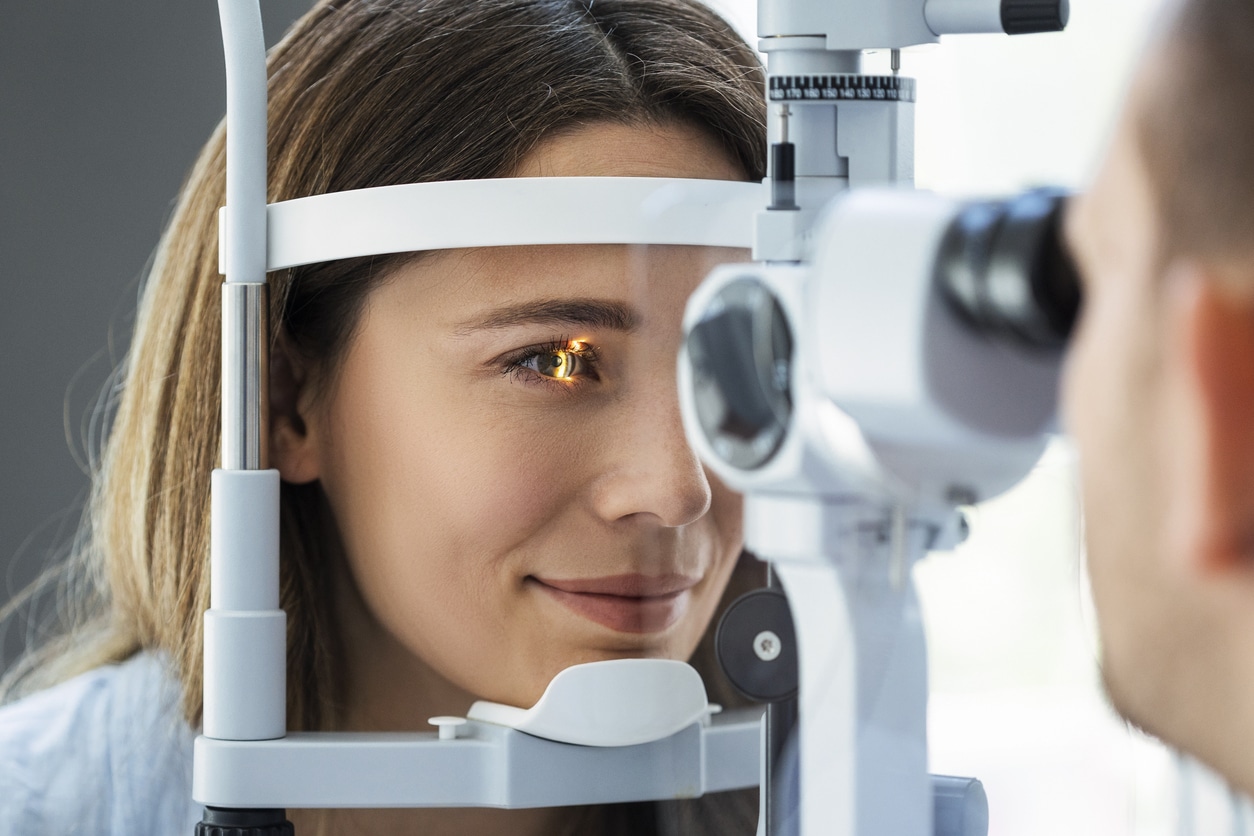 Woman pulling at her eyelid skin Woman undergoing a detailed eye examination to evaluate retinal health and vision changes related to an epiretinal membrane.